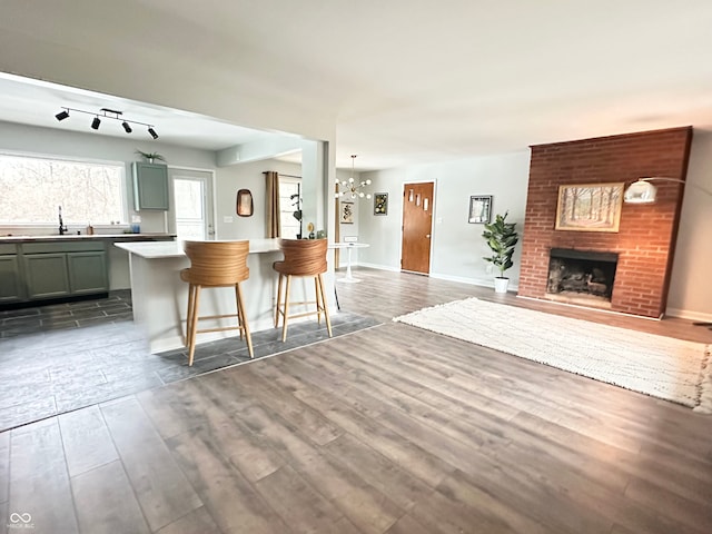 kitchen with sink, hanging light fixtures, a kitchen breakfast bar, dark hardwood / wood-style flooring, and a fireplace