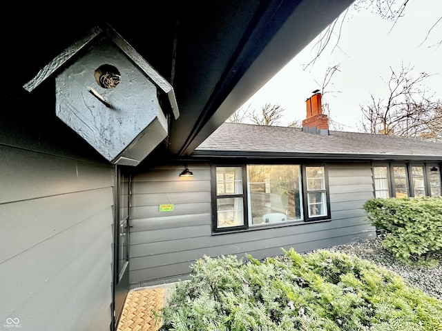 view of side of home featuring a chimney and a shingled roof