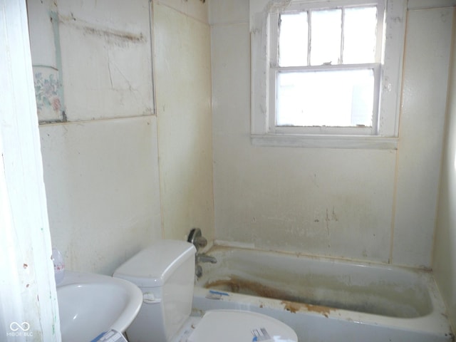 bathroom featuring a washtub and toilet