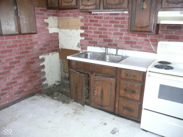 kitchen featuring brick wall, dark brown cabinetry, sink, and white range with electric stovetop