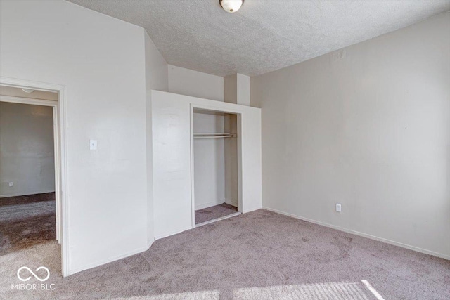 unfurnished bedroom with light colored carpet, a closet, and a textured ceiling