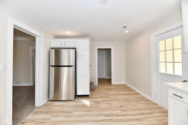 kitchen featuring light hardwood / wood-style flooring, stainless steel refrigerator, and white cabinets