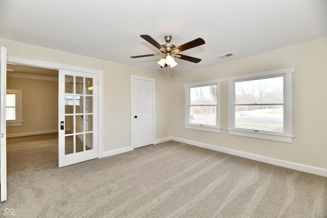 carpeted empty room featuring ceiling fan and french doors