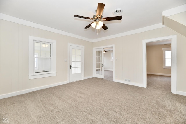 carpeted spare room featuring ornamental molding, ceiling fan, and french doors