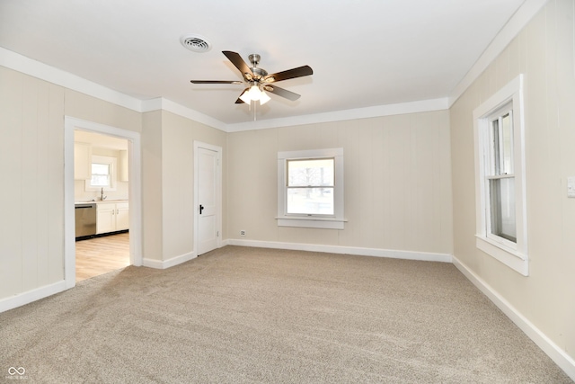 empty room featuring ornamental molding, sink, light colored carpet, and ceiling fan