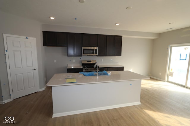 kitchen featuring light countertops, appliances with stainless steel finishes, light wood-type flooring, and a sink