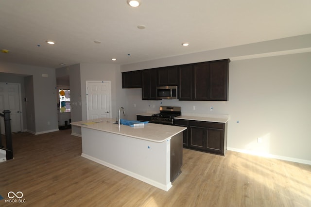 kitchen featuring stainless steel appliances, light wood-type flooring, a sink, and recessed lighting