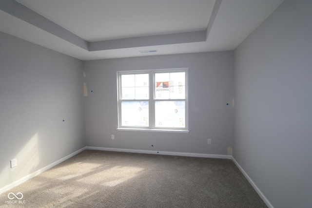 unfurnished room featuring carpet floors, a raised ceiling, visible vents, and baseboards