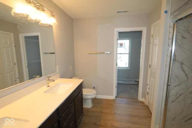 bathroom featuring double vanity, visible vents, toilet, wood finished floors, and a sink