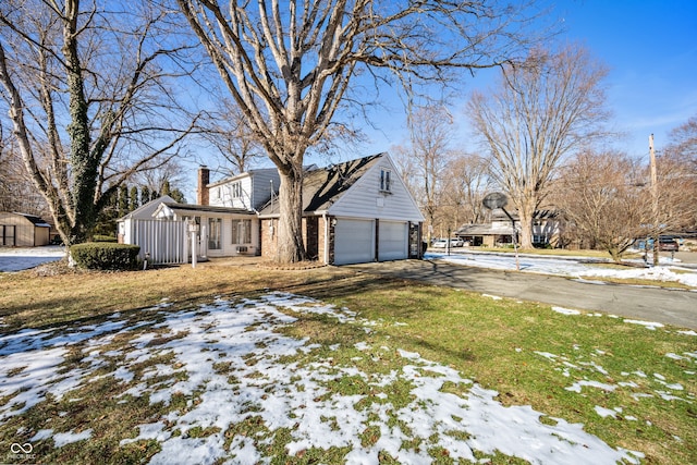 snow covered property featuring a garage and a lawn