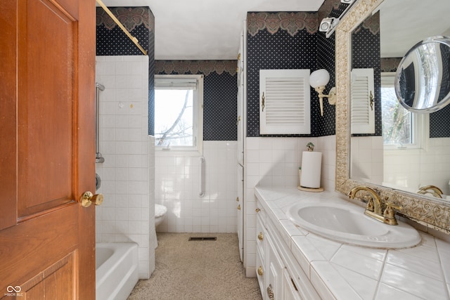 full bathroom with bathtub / shower combination, vanity, toilet, and tile walls