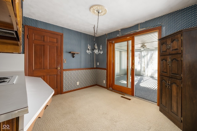 dining space with light carpet and ceiling fan with notable chandelier