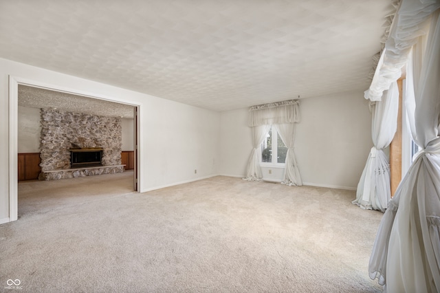 unfurnished living room featuring a stone fireplace, light carpet, and a textured ceiling