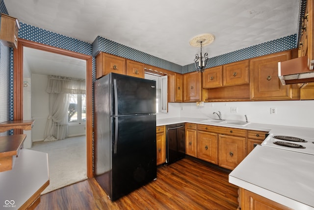 kitchen featuring dark wood-type flooring, sink, pendant lighting, range hood, and black appliances