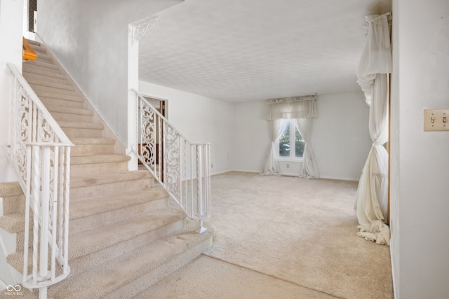 staircase with a textured ceiling and carpet