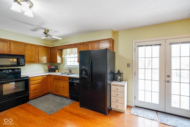 kitchen with sink, ceiling fan, black appliances, french doors, and light wood-type flooring