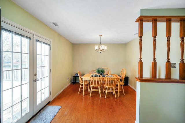 dining space featuring a notable chandelier, light hardwood / wood-style floors, and french doors