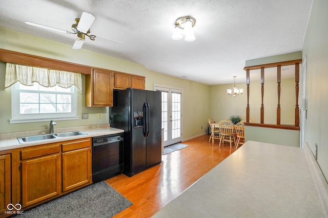 kitchen featuring pendant lighting, sink, light hardwood / wood-style flooring, black appliances, and a textured ceiling