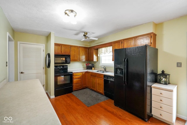 kitchen with dark wood-type flooring, sink, a textured ceiling, ceiling fan, and black appliances