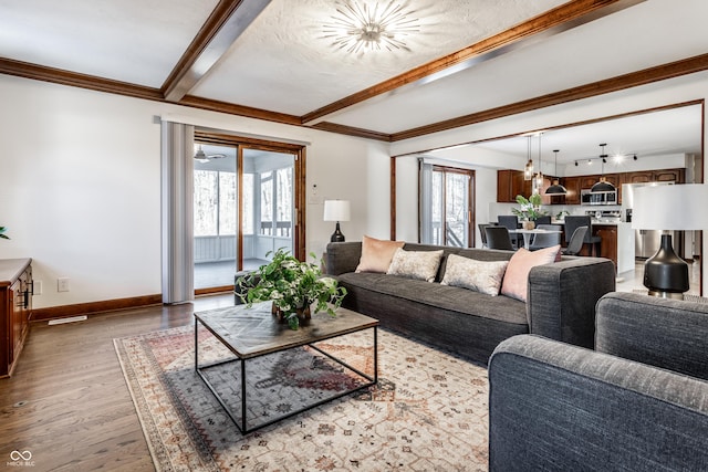 living room featuring beamed ceiling, ornamental molding, and light hardwood / wood-style flooring