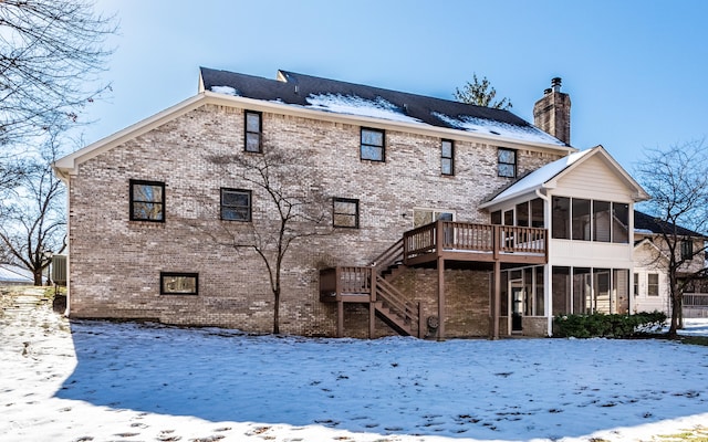 snow covered property featuring a deck and a sunroom