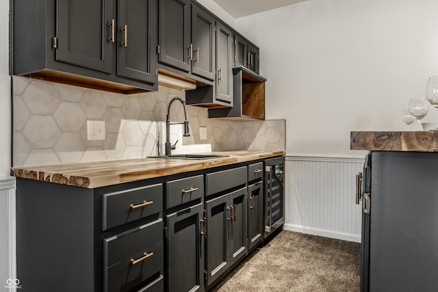 kitchen featuring butcher block countertops, sink, backsplash, dark colored carpet, and beverage cooler