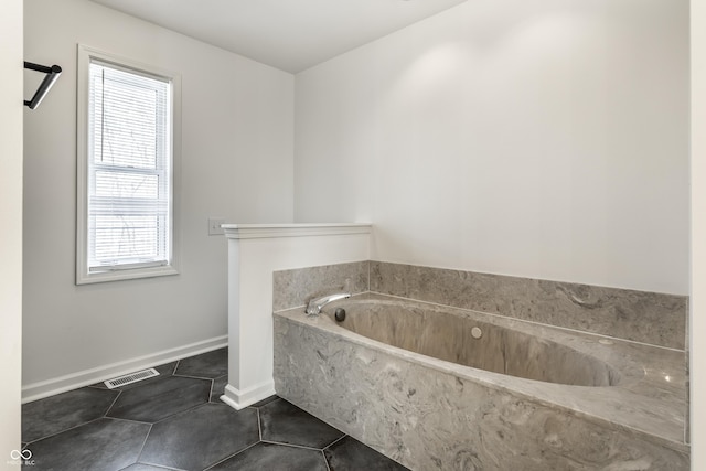 bathroom with tile patterned floors and a tub