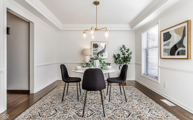 dining area featuring crown molding, dark wood-type flooring, and an inviting chandelier