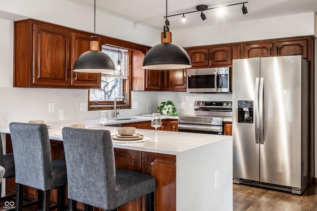 kitchen with appliances with stainless steel finishes, dark hardwood / wood-style floors, pendant lighting, sink, and a center island