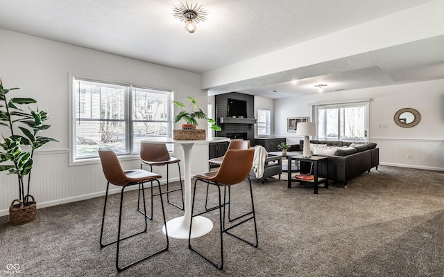 dining space featuring a brick fireplace and carpet