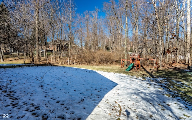 yard layered in snow featuring a playground