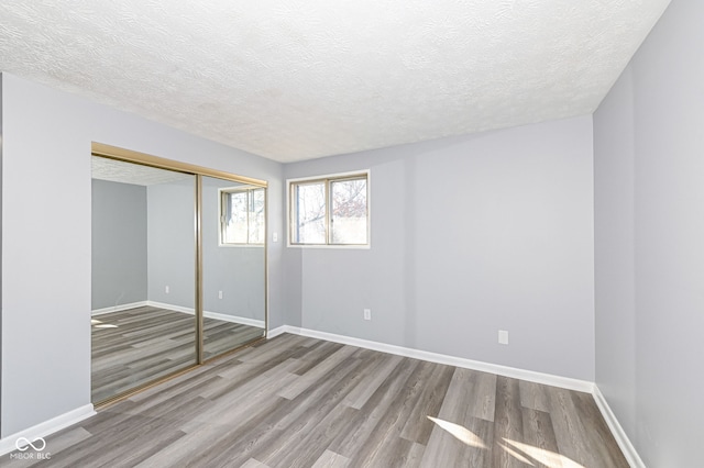 unfurnished bedroom featuring hardwood / wood-style floors, a textured ceiling, and a closet