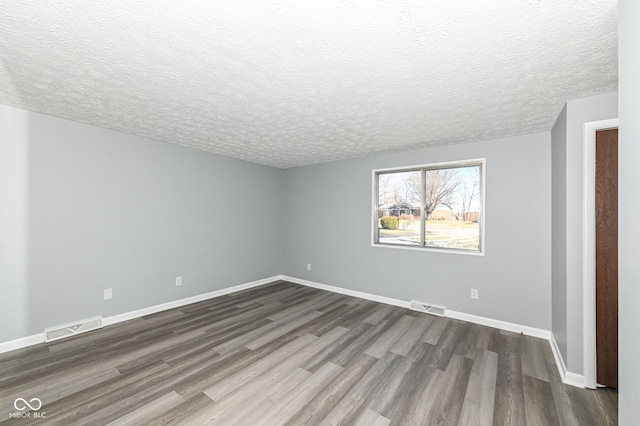 spare room with dark hardwood / wood-style flooring and a textured ceiling