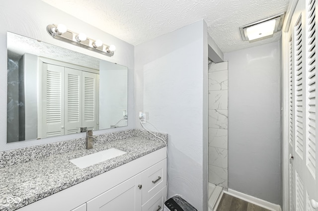 bathroom with vanity, hardwood / wood-style flooring, a shower, and a textured ceiling