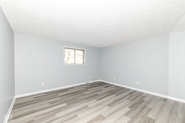 empty room featuring a textured ceiling and light wood-type flooring