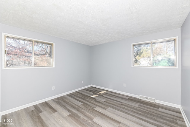 unfurnished room with hardwood / wood-style flooring and a textured ceiling