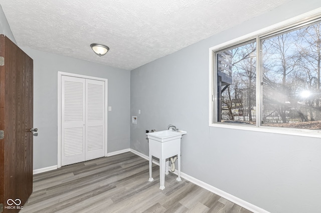 clothes washing area with hardwood / wood-style floors, a healthy amount of sunlight, and washer hookup