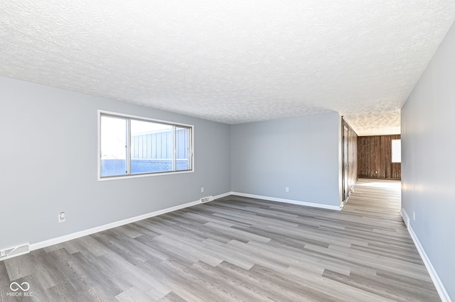 unfurnished room with a textured ceiling and light wood-type flooring