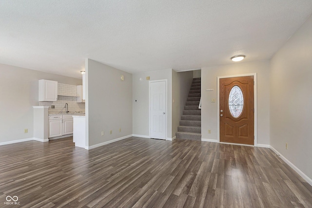 foyer with dark wood-type flooring, sink, and a textured ceiling