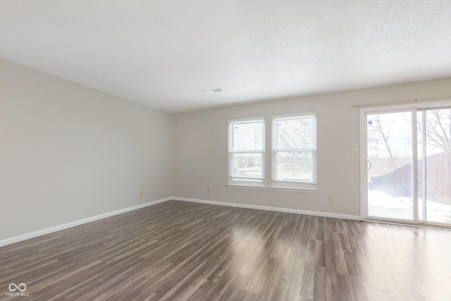 empty room with dark wood-type flooring and a textured ceiling