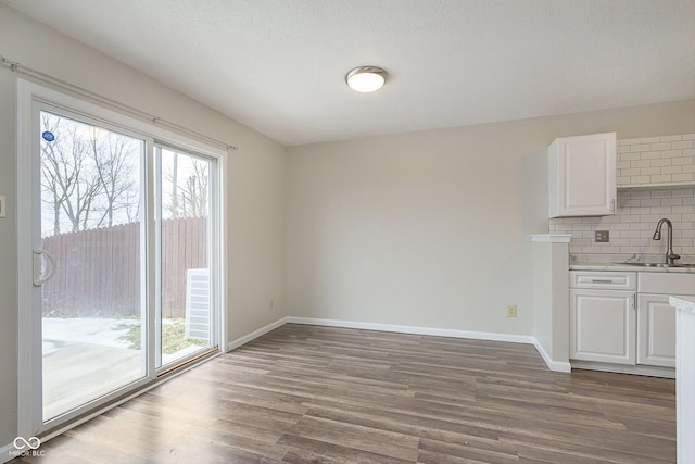 unfurnished dining area featuring sink, wood-type flooring, and a textured ceiling