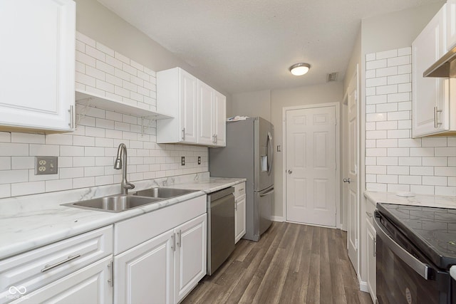 kitchen with appliances with stainless steel finishes, sink, white cabinets, dark hardwood / wood-style flooring, and a textured ceiling