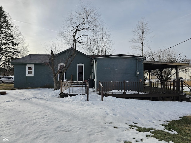 snow covered back of property with a deck