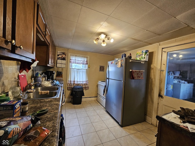 kitchen featuring sink, light tile patterned floors, stainless steel refrigerator, white electric range oven, and washer / clothes dryer