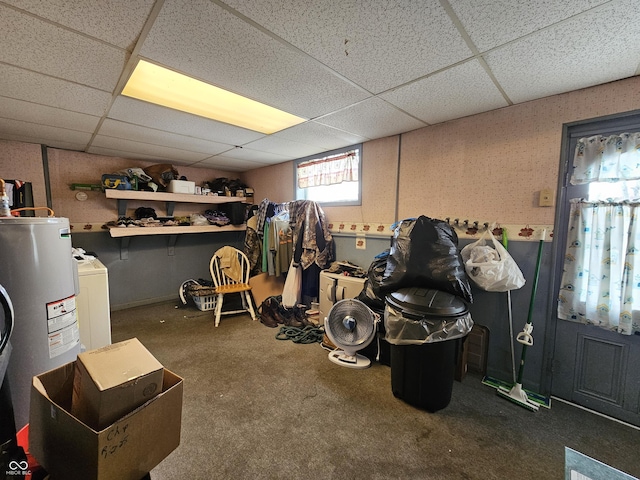 basement with water heater, washer / dryer, carpet flooring, and a drop ceiling