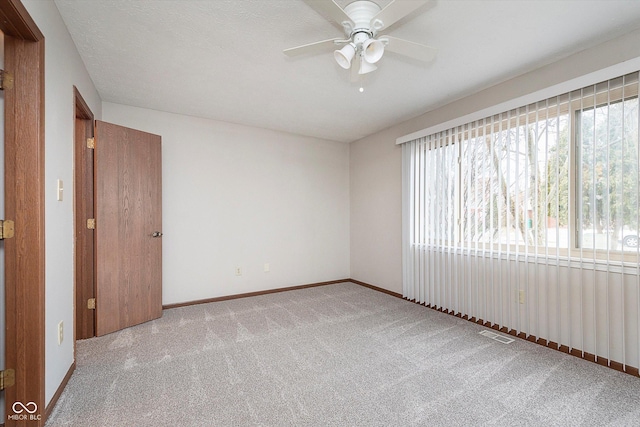 empty room featuring light carpet, a textured ceiling, and ceiling fan