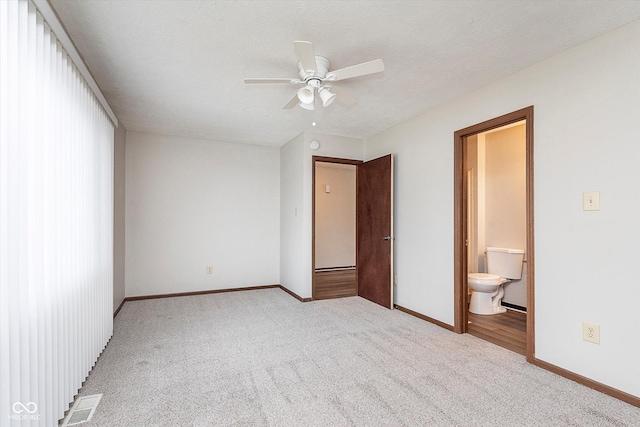 unfurnished bedroom with ceiling fan, connected bathroom, light carpet, and a textured ceiling