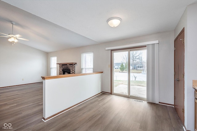 kitchen featuring lofted ceiling, a brick fireplace, a textured ceiling, kitchen peninsula, and hardwood / wood-style flooring