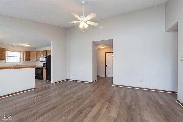 unfurnished living room with dark hardwood / wood-style floors, sink, and ceiling fan