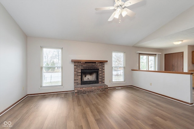 unfurnished living room featuring hardwood / wood-style floors, vaulted ceiling, and a brick fireplace